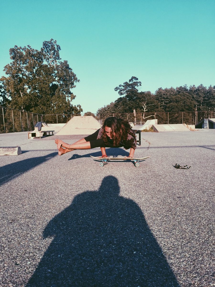 Sarah in an arm balance on a skateboard at a skatepark