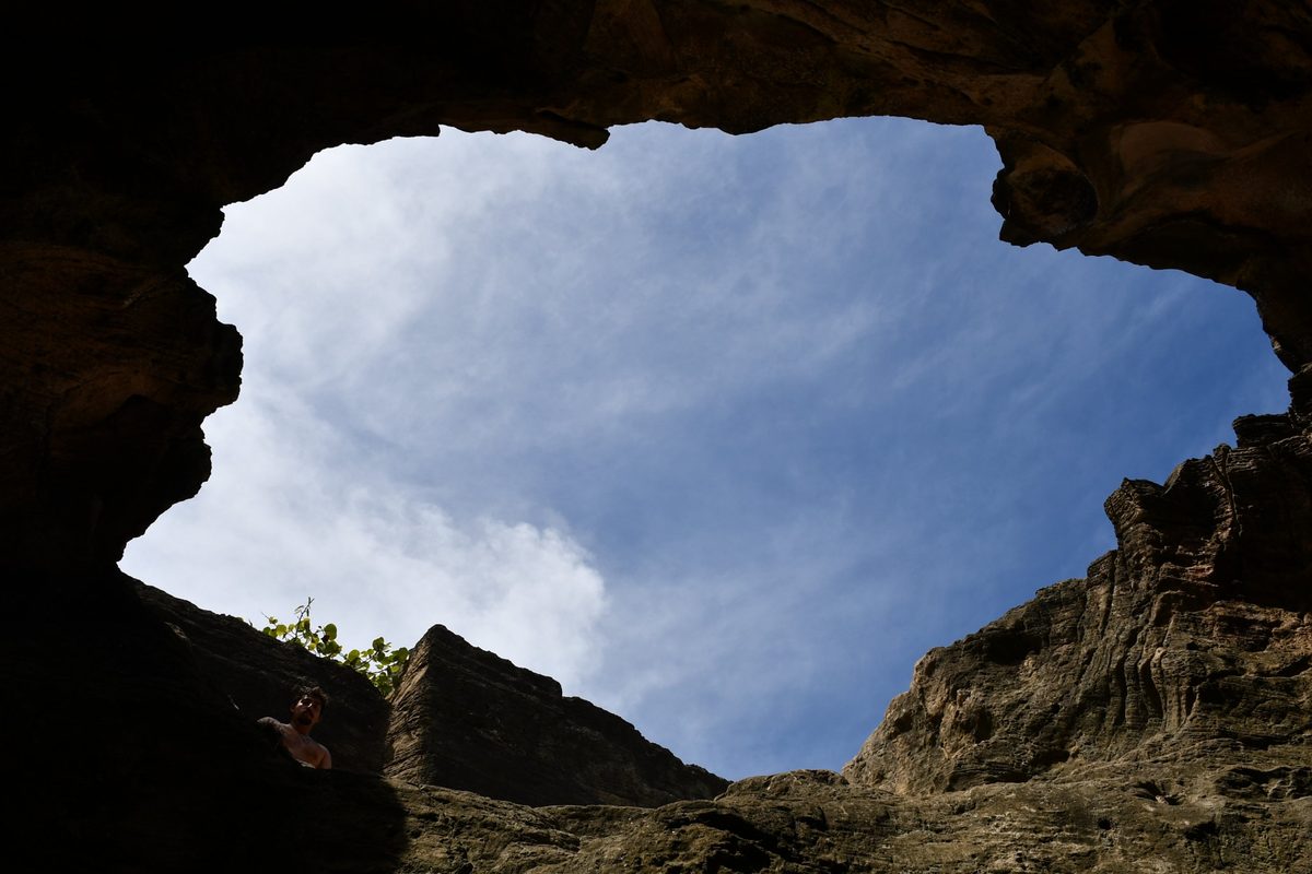 Looking up through a cave opening to blue sky