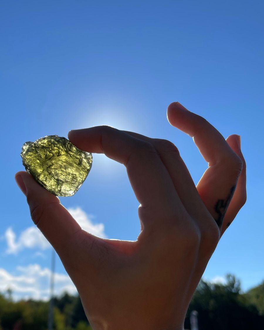 A piece of green moldavite held up to the sun